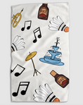 Load image into Gallery viewer, A white kitchen towel featuring a playful pattern of badminton shuttlecocks, black musical notes, a brass trumpet, a blue fountain, and brown bottles labeled 'BBQ'.