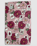 Load image into Gallery viewer, A square textile item, likely a tea towel or hand towel, featuring a pink background with a repeating pattern of dark pink and burgundy flowers, green leaves, and white playing cards.