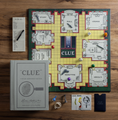 Load image into Gallery viewer, Clue vintage codex edition board game set arranged on a wooden tabletop, including the board, instruction booklet, play cards, dice, and game box.