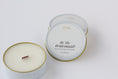 Load image into Gallery viewer, Two round candles in white tins with gold rims on a clean white background. One tin is open, showing a white wax surface and a small brown wood wick.
