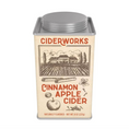 Load image into Gallery viewer, A square metal tin of Ciderworks Cinnamon Apple Cider on a plain white background. The tin has a cream-colored label with brown illustrations of a cider mill, apple, and cider glasses, and red lettering.
