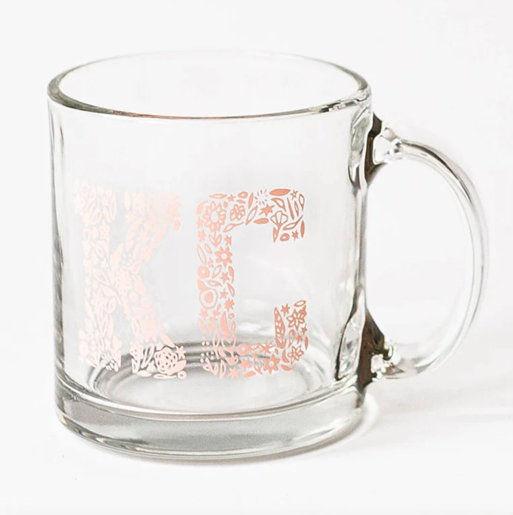 a glass mug with the letters "KC" on it in a pink floral pattern
