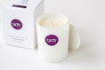 Load image into Gallery viewer, A white wax candle in a white glass jar with a purple circular label reading 'CATS', shown next to its white box packaging on a clean white background.
