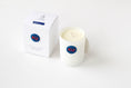 Load image into Gallery viewer, A white glass jar candle with cream-colored wax and a blue circular 'KU' logo, shown next to its white packaging box on a clean white background.
