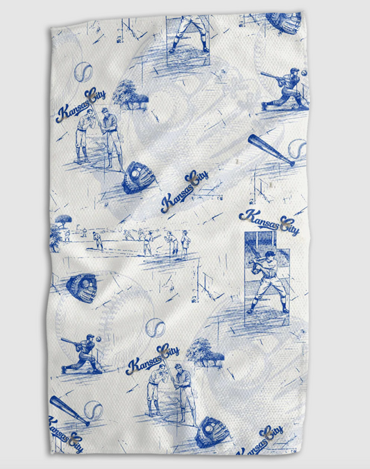A white and blue patterned kitchen towel that features different scenes from Kansas City Royals baseball, including baseball players hitting the ball and winding up to hit the ball, and illustrations of baseballs, baseball mitts, and the words "Kansas City"