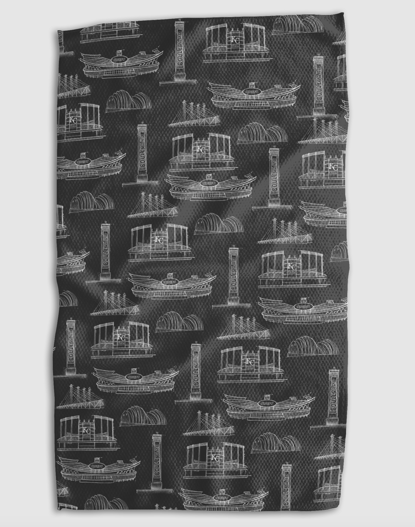A rectangular black towel or cloth featuring an all-over white line-art pattern of different Kansas City landmarks, shown flat against a light gray background.