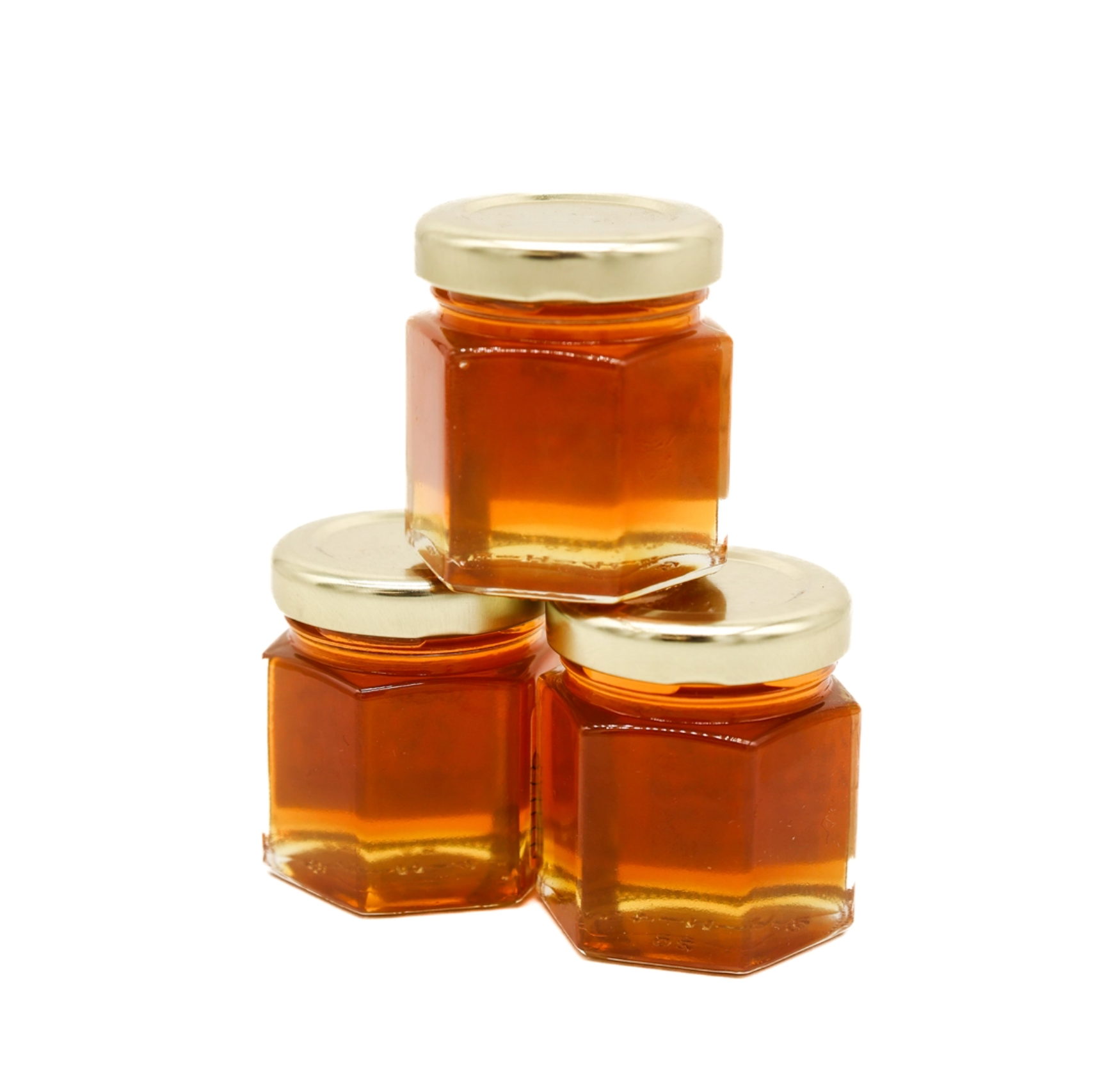 Three small hexagonal glass jars filled with amber honey, arranged in a pyramid stack with shiny gold metal lids on a plain white background.