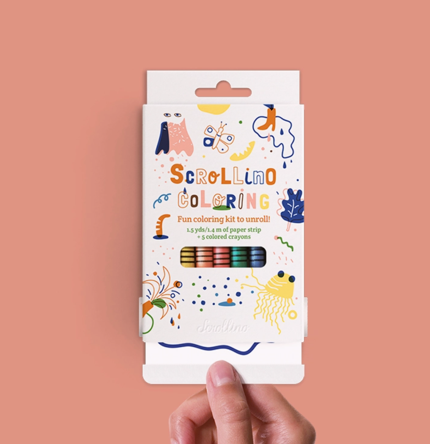A hand holds the packaging for scrollino coloring book, filled with crayons and 1.5yds of paper to color on. 