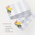 Load image into Gallery viewer, A stack of note cards with a white and light blue striped design, decorated with a yellow lemon, pink flowers, and green leaves. One card is shown flat with a printed example name and table number.
